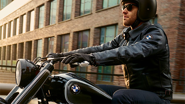A driver sits relaxed on his motorcycle, wearing a FlatTwin men’s leather jacket.
